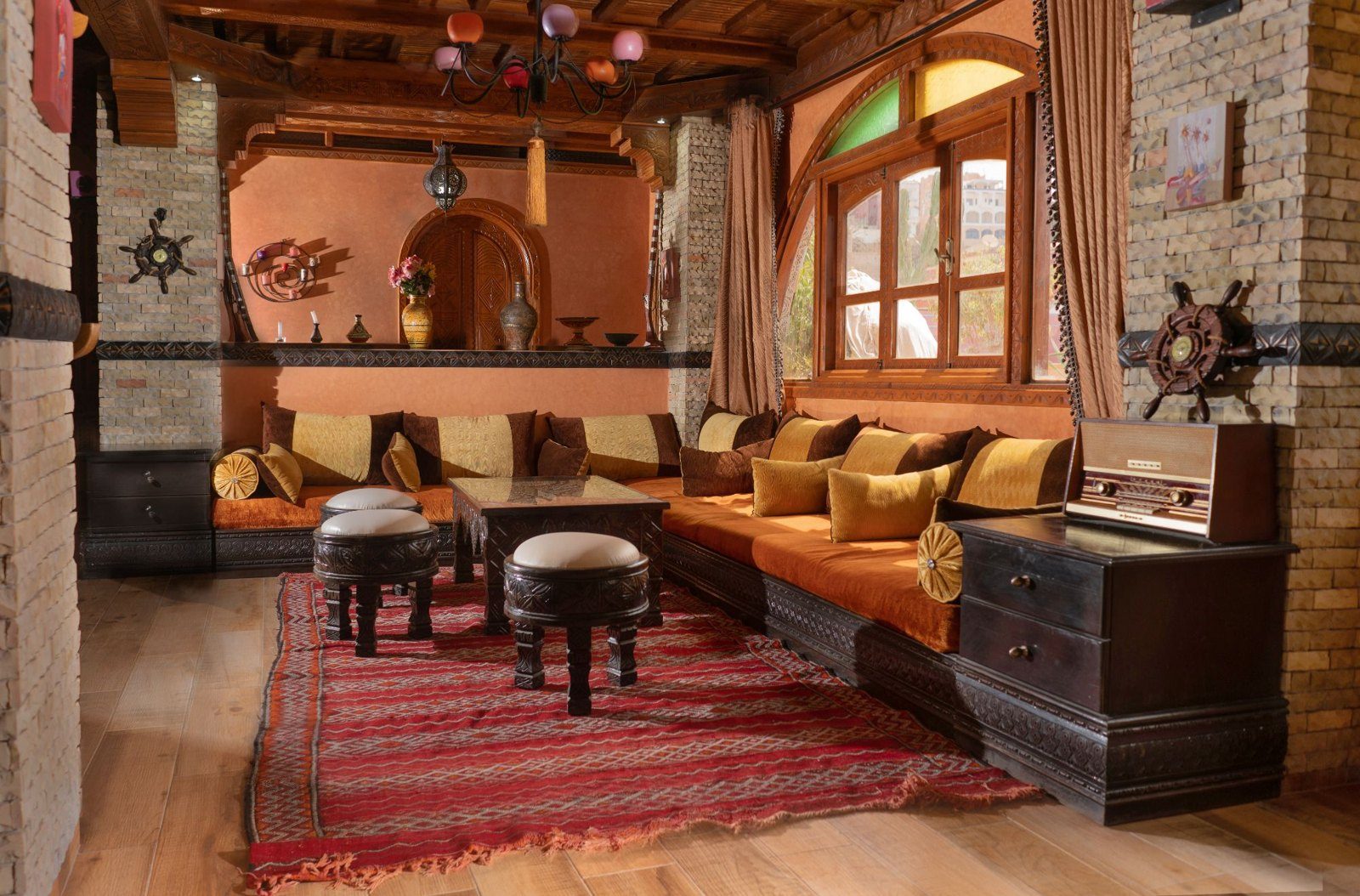 Moroccan lounge with carved wood, orange cushions and a red rug