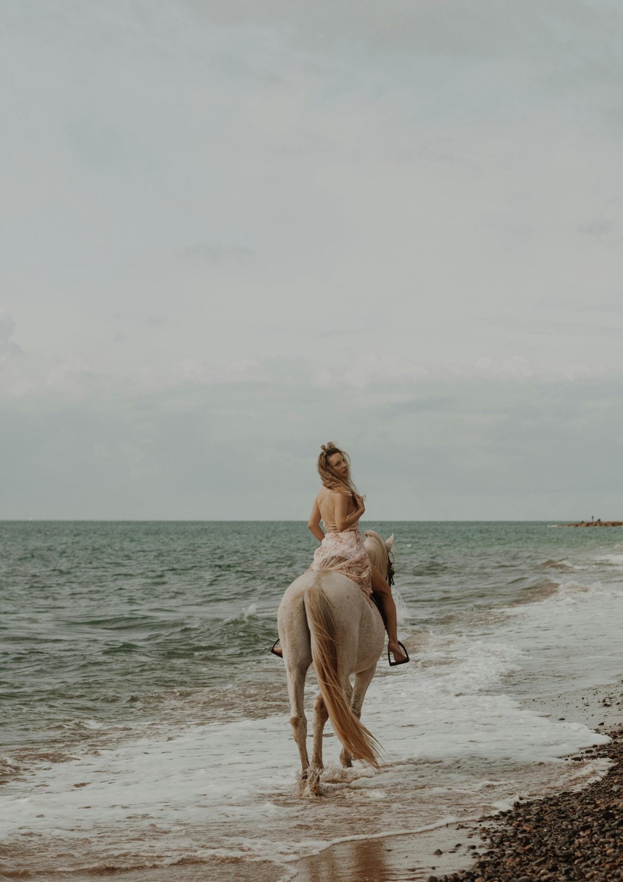Woman riding a white horse through the shallows