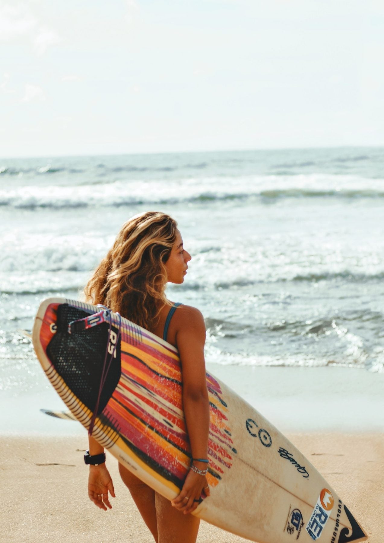 Surfer carrying her board towards the waves in Morocco